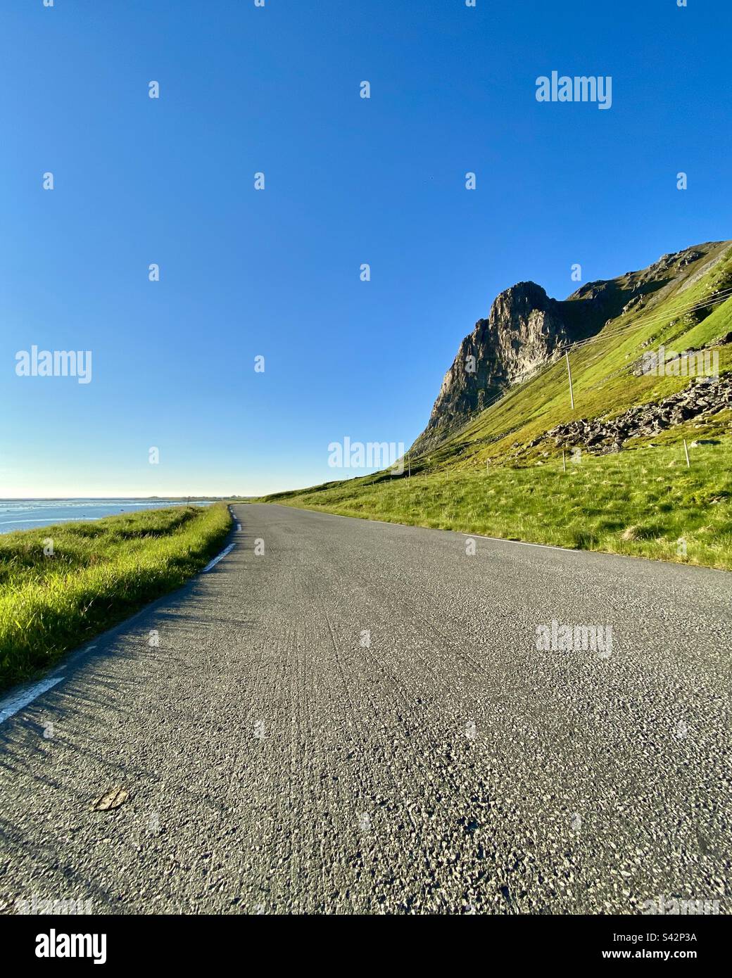 Asphalt road by the sea on a sunny late summer evening in Lofoten islands, Norway. Stock Photo