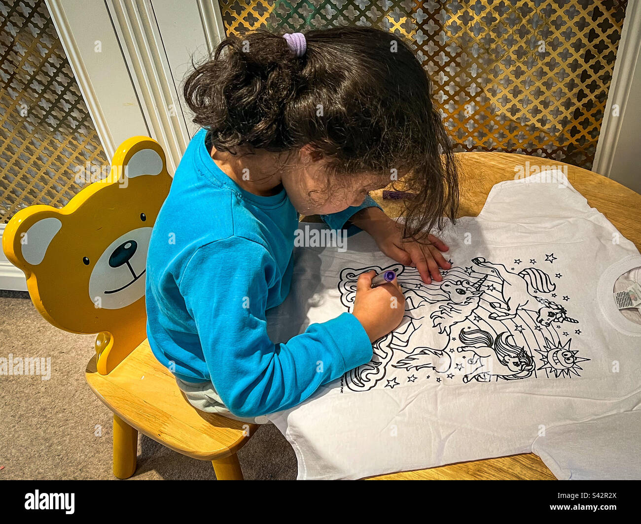 Young girl colouring t-shirt at home Stock Photo