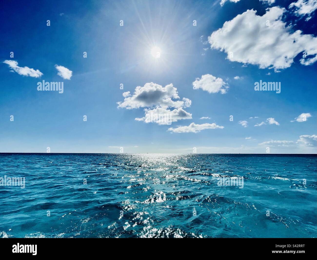 Caribbean Blue Horizon line, on blue sea on blue sky with clouds and sun - Smartphone Captured Stock Image