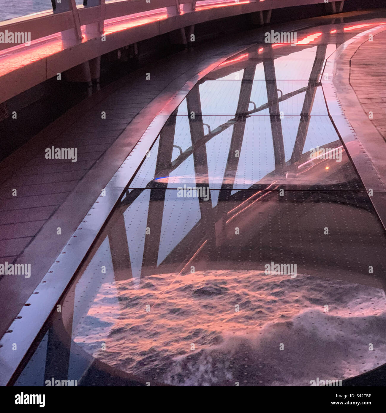 November, 2022, Looking through the transparent floor of the Seawalk,towards the ocean as it reflects the sunset, on a Royal Princess cruise, sailing away from Ensenada, Baja California, Mexico - Smartphone Captured Stock Image