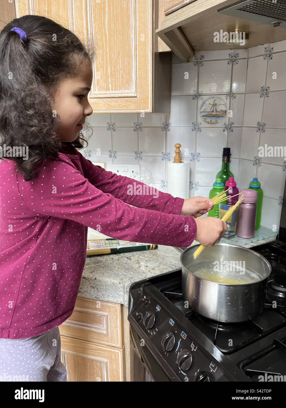 Young girl helping cook spaghetti on a gas stove Stock Photo Alamy