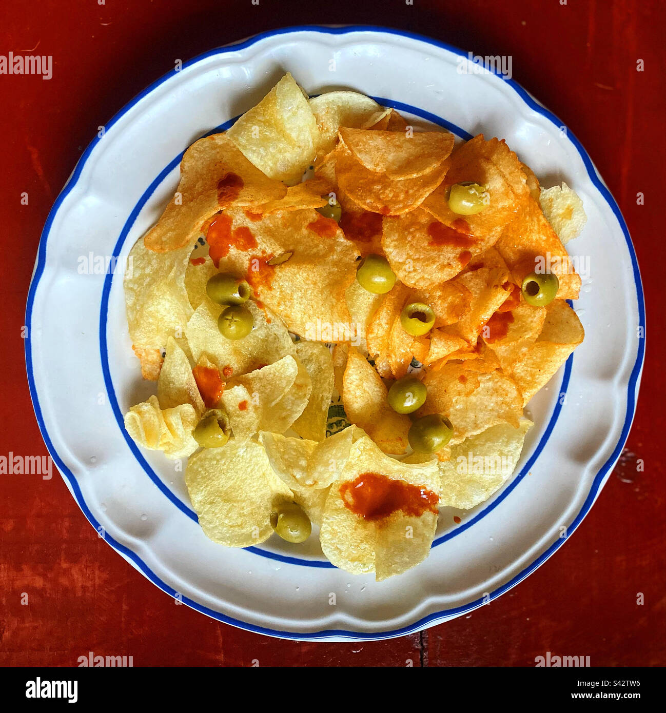 Fried potato chips with red spicy sauce and olives in Mexico Stock