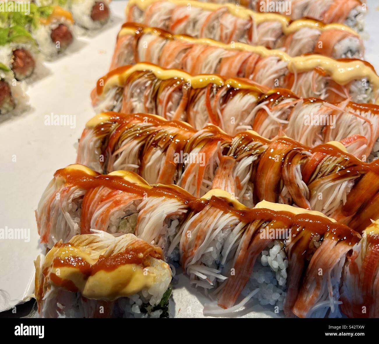 A beautiful tray of sushi wrapped in imitation crab at a sushi bar in