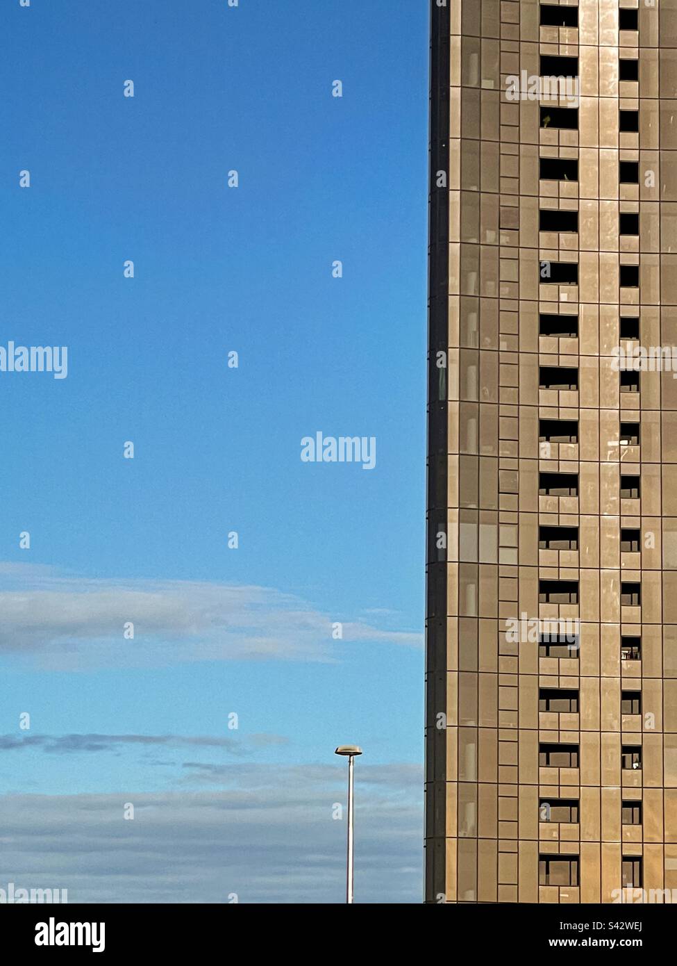 Low angle shot of building facade against blue sky with clouds - Smartphone Captured Stock Image