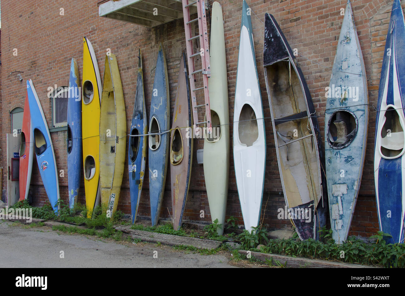 A bunch of old kayaks or end up against the brick wall Stock Photo