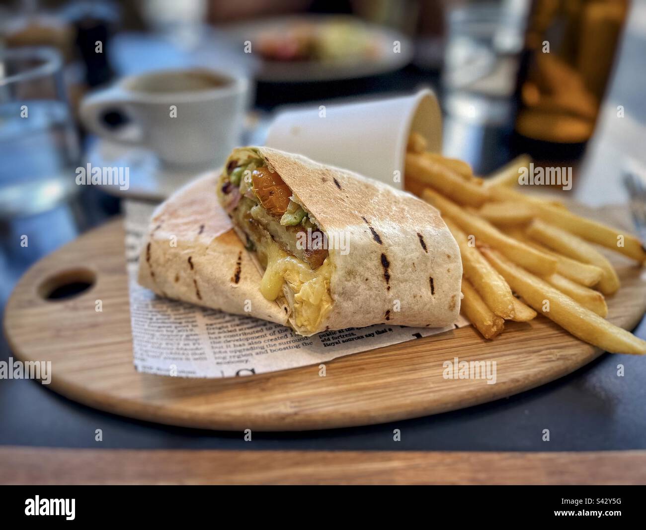 burrito with scrambled eggs and veggies and French fries on wooden serving board on table. - Smartphone Captured Stock Image
