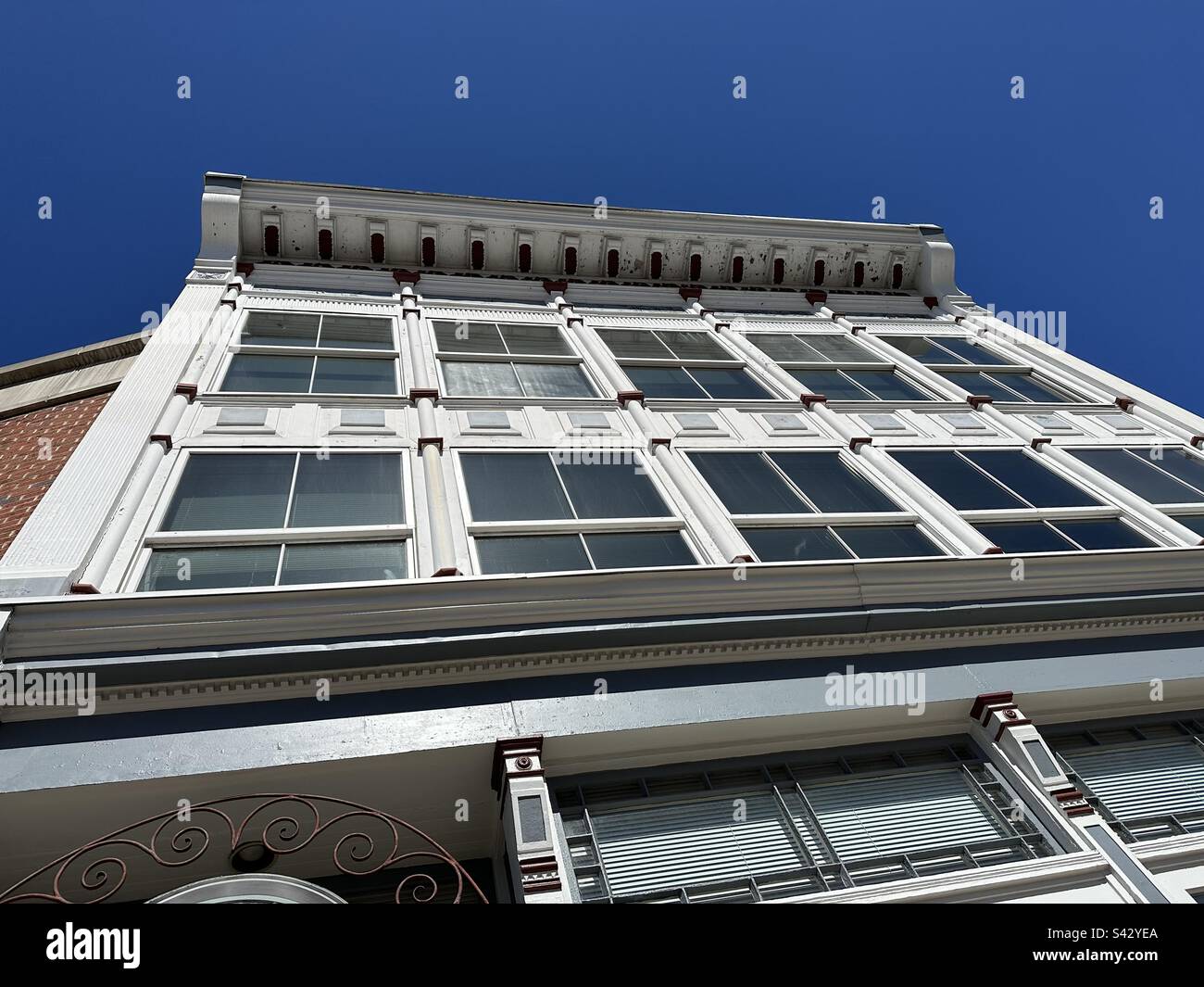 Looking up at a white, vintage building on Water Street in Norwich, Connecticut, USA. Blue sky in the background. - Smartphone Captured Stock Image