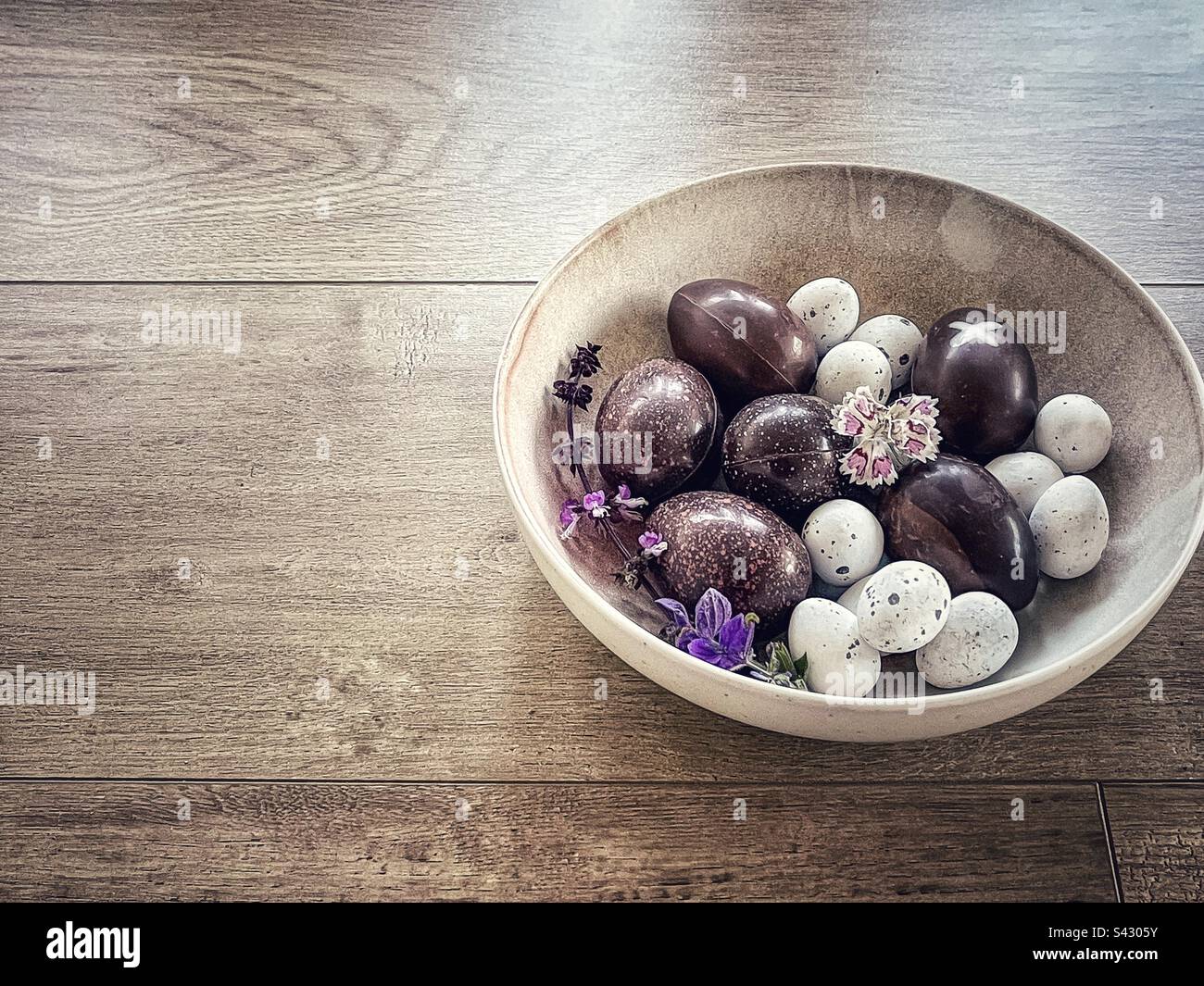 Easter chocolate and praline eggs in bowl on wooden table. Stock Photo