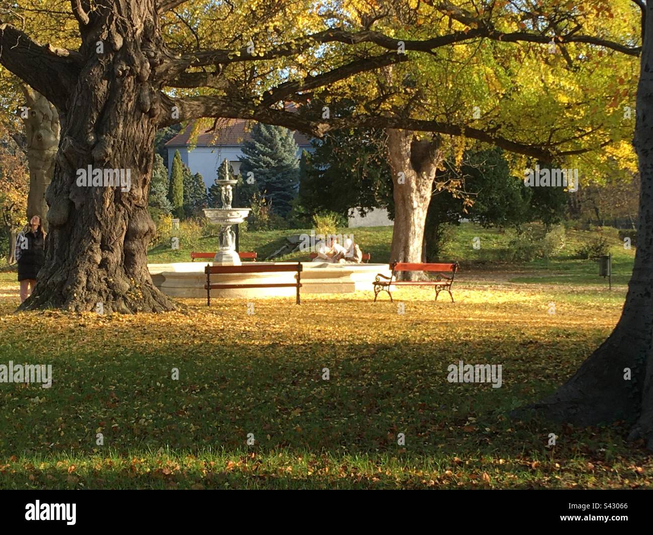 Fountain and relaxing people sitting on bench in park of Lenck-villa in autumn, Sopron, Hungary - Smartphone Captured Stock Image