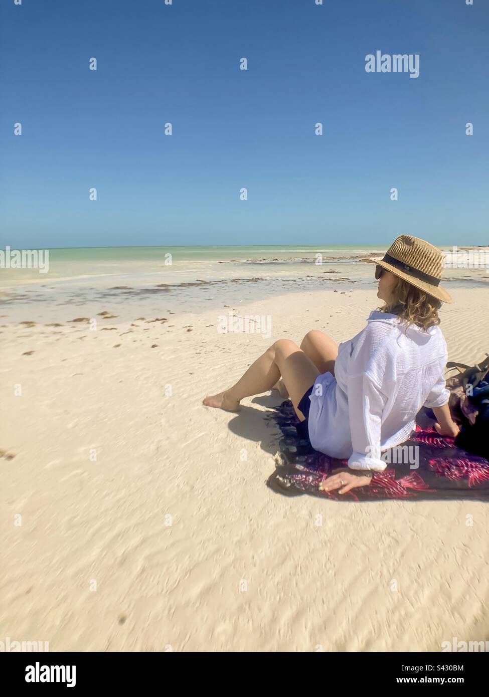 Beautiful woman sits on a sarong taking in the beauty of Punta Mosquito on Holbox Island. - Smartphone Captured Stock Image