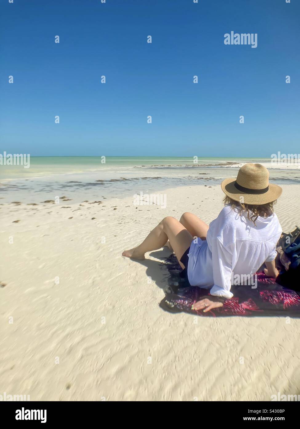 Beautiful woman sits on a sarong taking in the beauty of Punta Mosquito on Holbox Island. - Smartphone Captured Stock Image