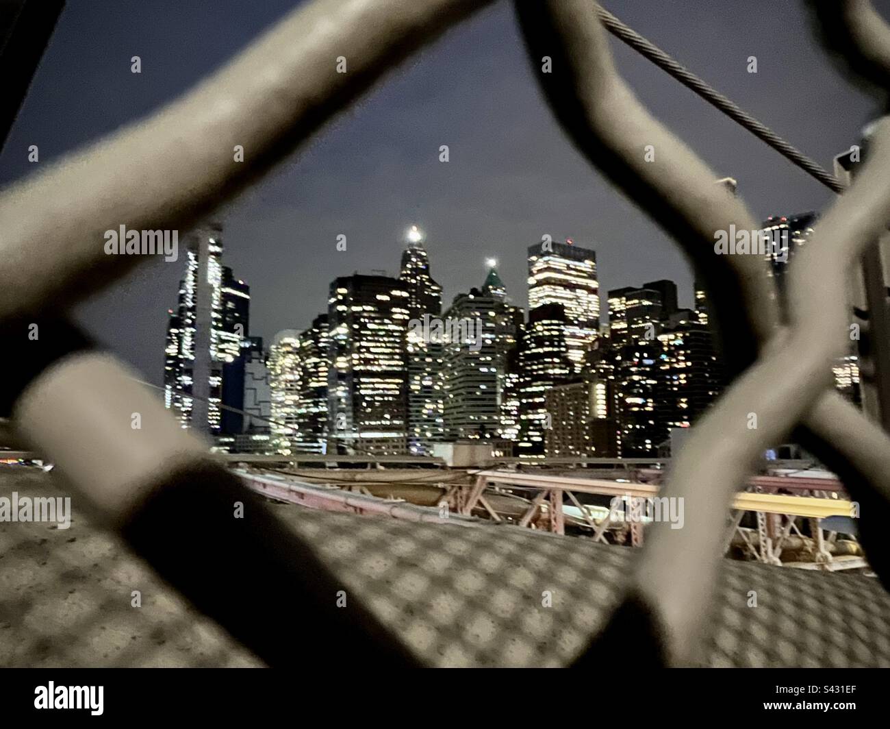 Night view of illuminated buildings in New York through an iron fence