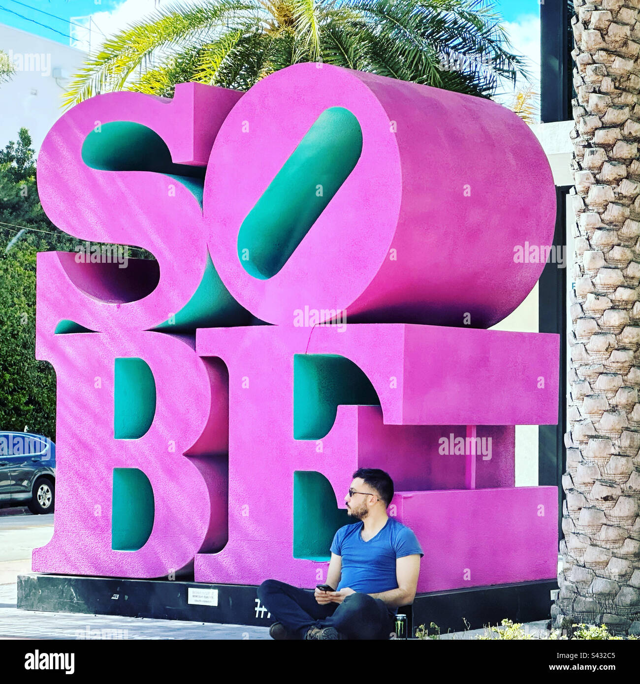 January, 2023, man sitting by SOBE sculpture, South Beach, Miami Beach, Florida, United States Stock Photo