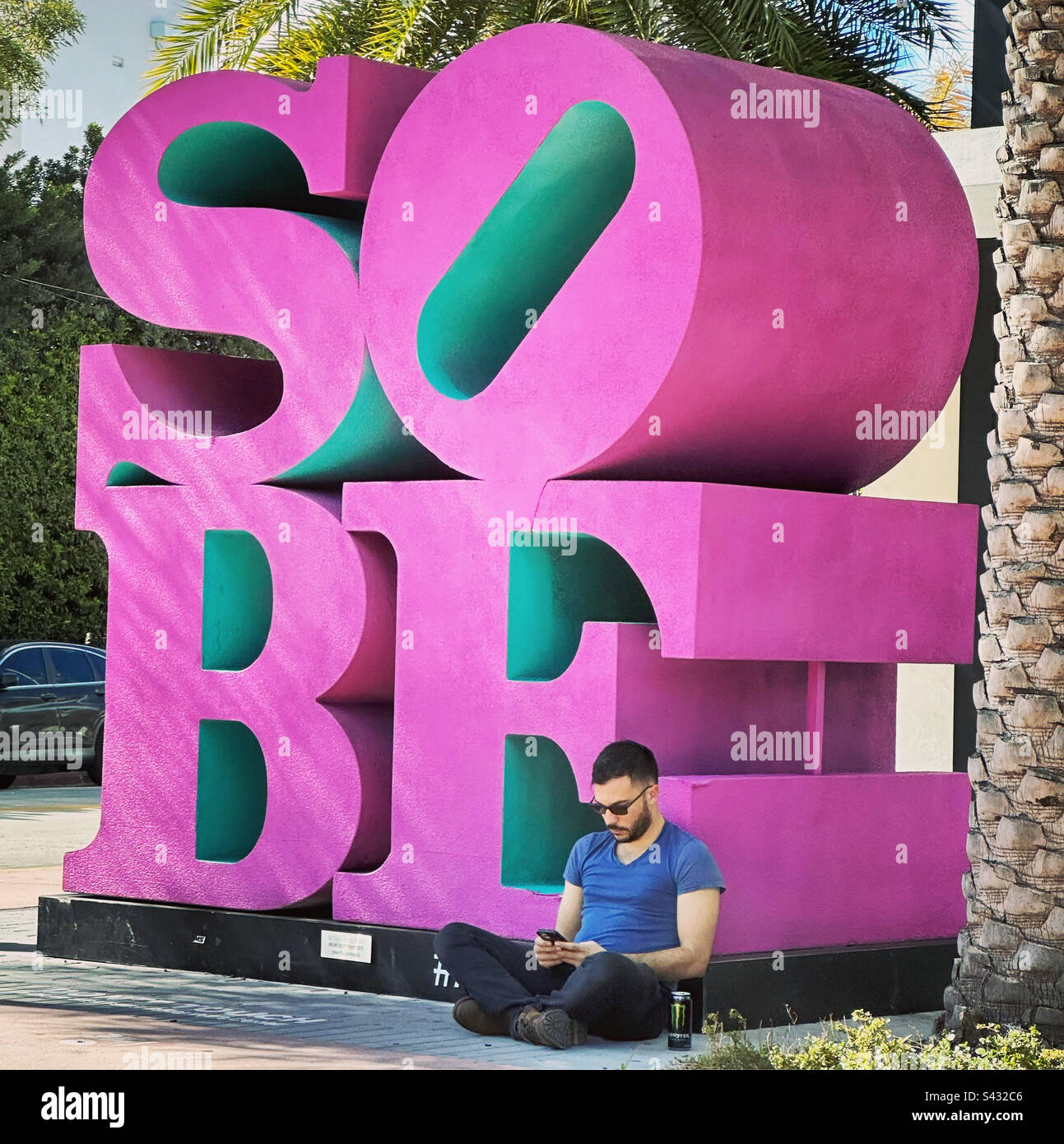 January, 2023, man sitting by SOBE sculpture, South Beach, Miami Beach, Florida, United States - Smartphone Captured Stock Image