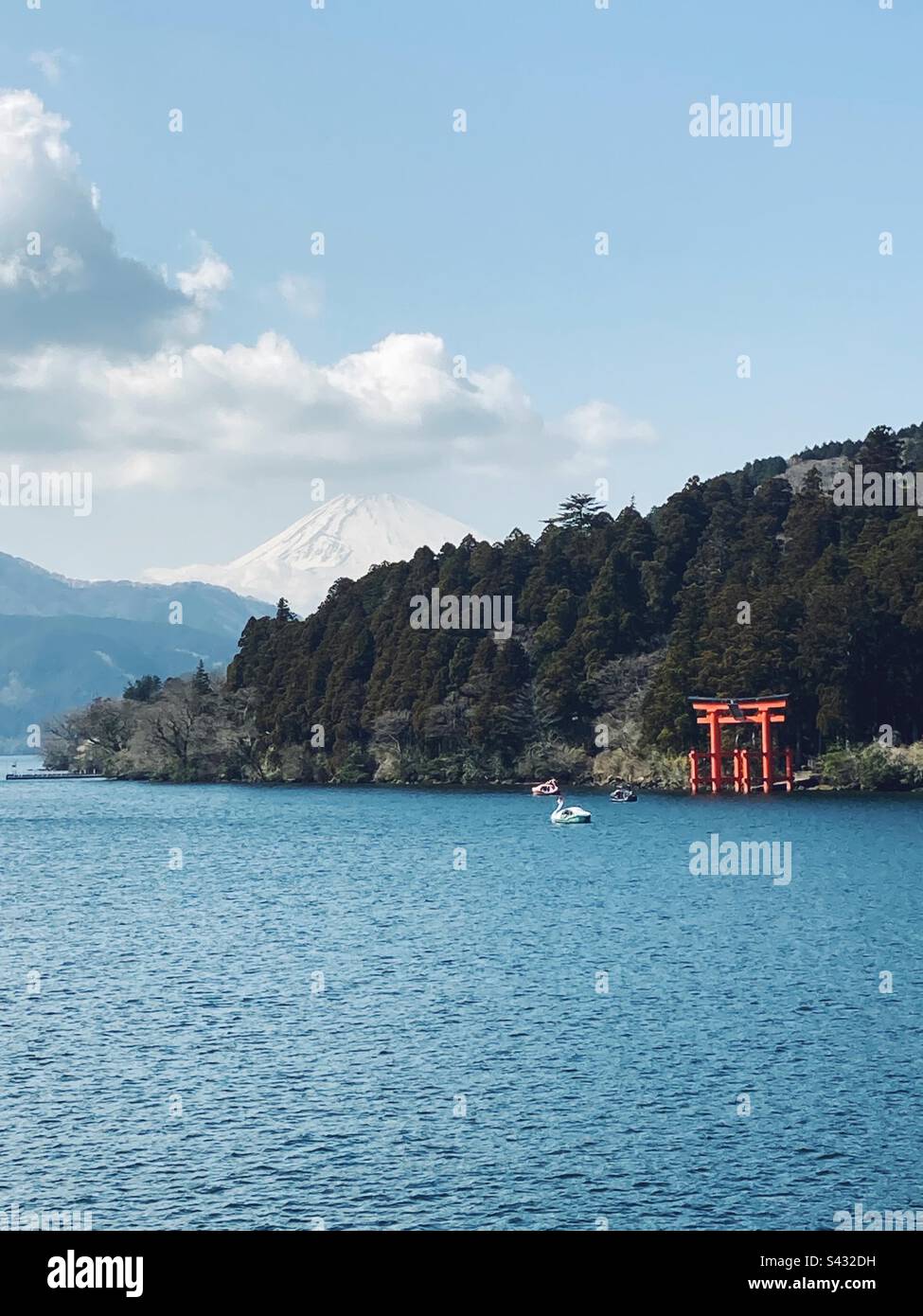 Mount Fuji just visible behind a hill with a torii on the edge of Lake Asahi, Hakone, Japan - Smartphone Captured Stock Image