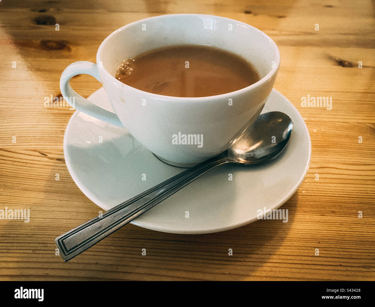 A cup of tea with a saucer and teaspoon. - Smartphone Captured Stock Image