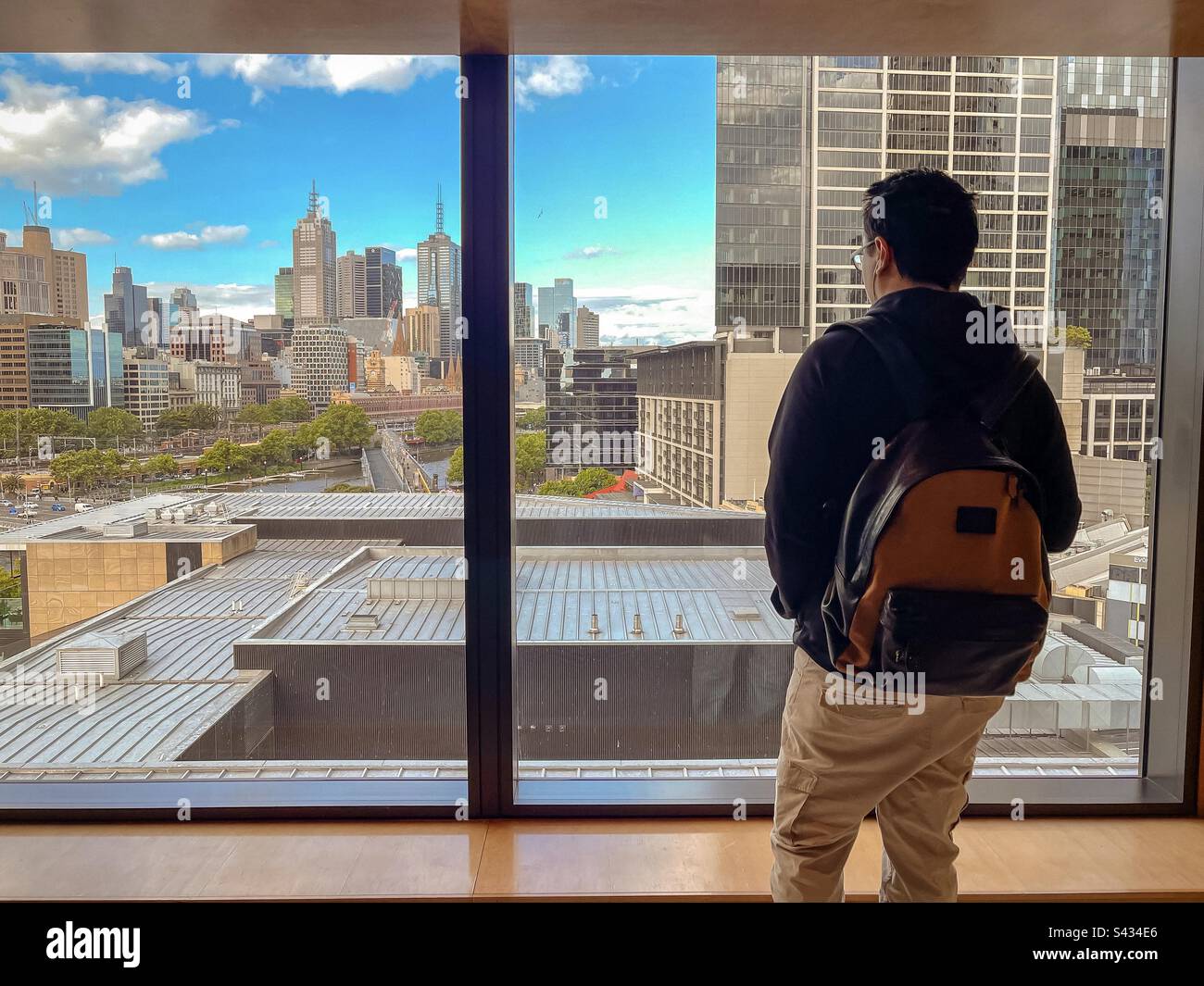 Rear view of man looking at window view of buildings and city skyline in Melbourne, Australia. - Smartphone Captured Stock Image Rear view of man looking at window view of buildings and city skyline in Melbourne, Australia. - Smartphone Captured Stock Image