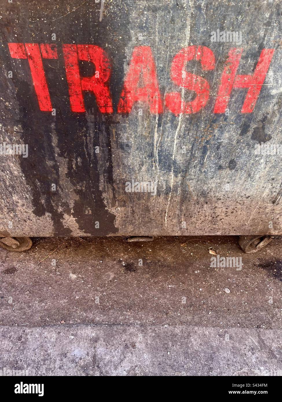 Dirty city alley dumpster, says TRASH in red letters. Includes print space. Stock Photo