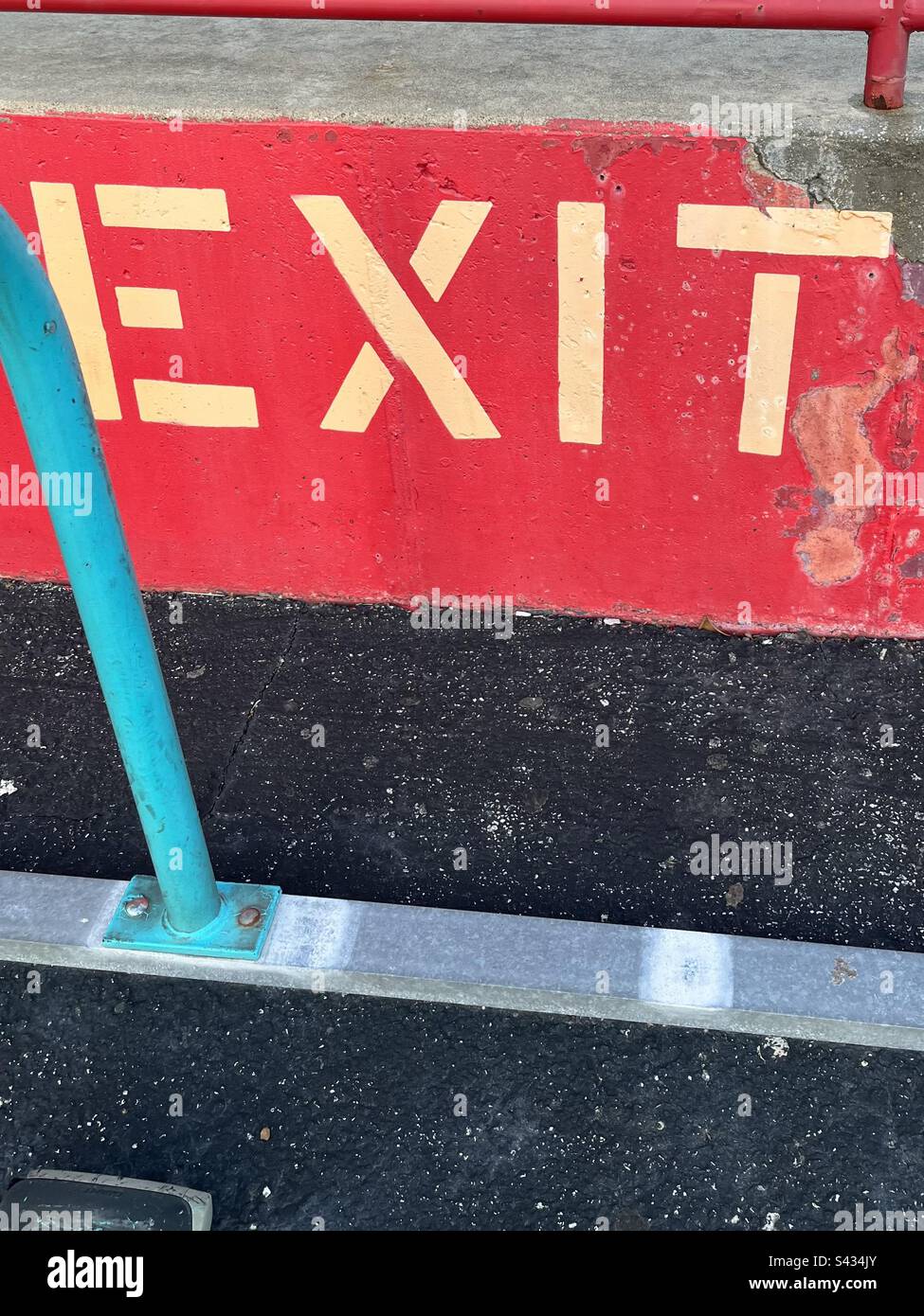 Grunge look. Big red sign, says EXIT with blue detail on black pavement. Includes print space. - Smartphone Captured Stock Image