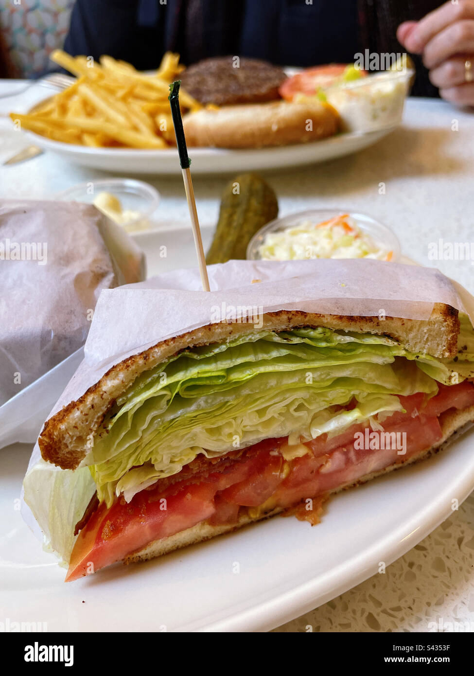 Bacon lettuce and tomato sandwich across from a cheeseburger deluxe platter and a new York city diner, 2023, USA - Smartphone Captured Stock Image