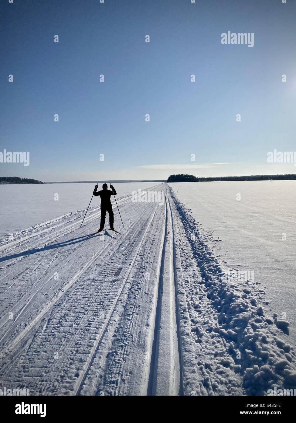A woman cross-country skiing on an outdoor sports holiday on a frozen lake in the Arctic Circle region of Finland - Smartphone Captured Stock Image