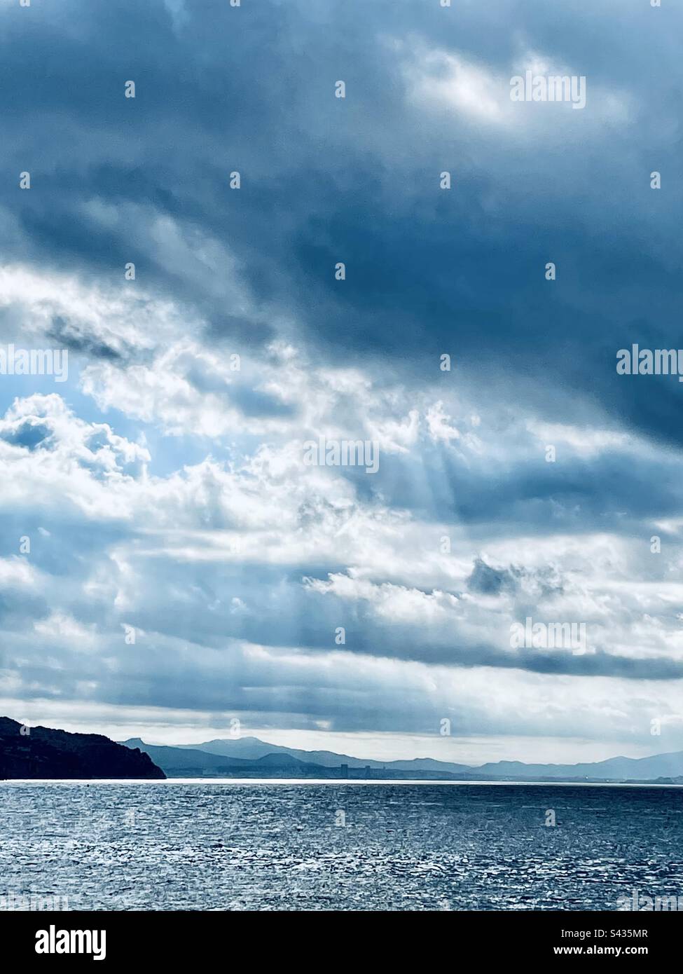 Seascape with sun rays going through the clouds on the Mediterranean Sea. Light reflecting the horizon line. - Smartphone Captured Stock Image