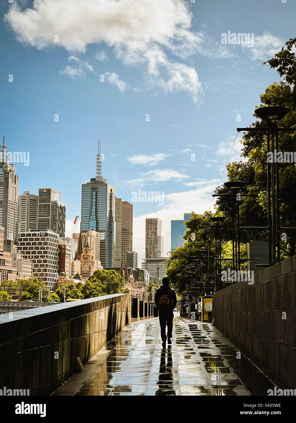 rear view of man walking on paved footpath against buildings and urban skyline in Melbourne, Australia. - Smartphone Captured Stock Image rear view of man walking on paved footpath against buildings and urban skyline in Melbourne, Australia. - Smartphone Captured Stock Image