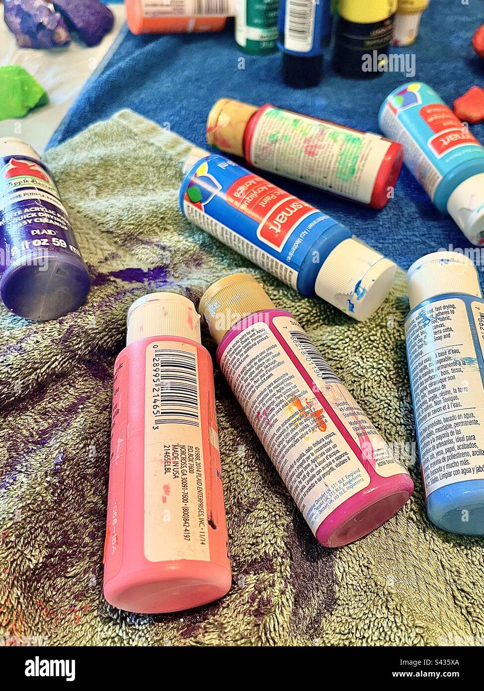Part 1 of set. Messy artist’s loft, closeup of several colorful paint containers on drop cloth. - Smartphone Captured Stock Image