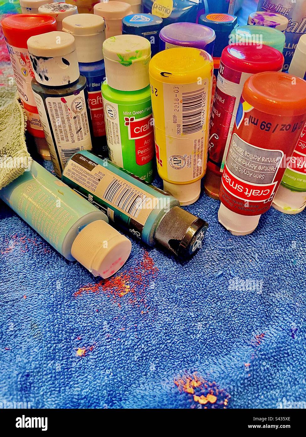 Colorful artist’s paint set on messy paint splattered blue textured drop cloth. Includes print space. - Smartphone Captured Stock Image