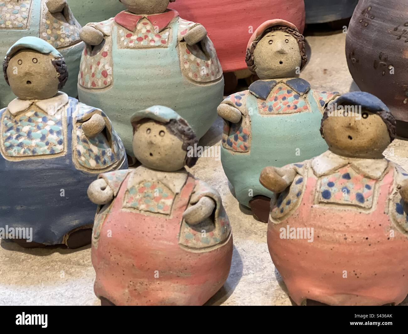 Hand made colourful pot people dressed in dungarees Stock Photo