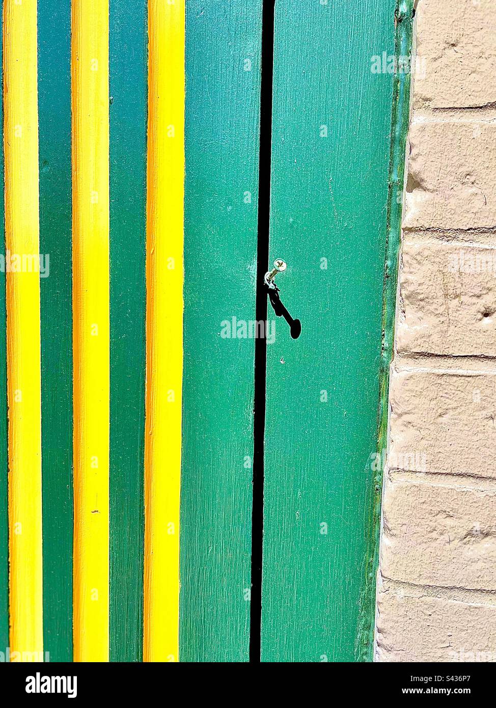 Green wooden wall with three yellow vertical stripes meets white brick wall near right side. Includes print space. - Smartphone Captured Stock Image