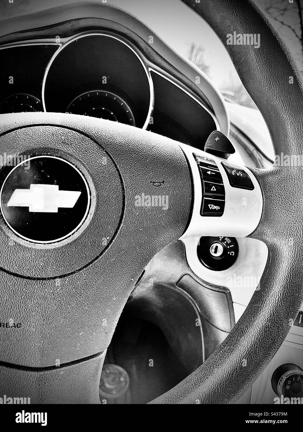 Black and white steering wheel with Chevy logo. Includes print space. - Smartphone Captured Stock Image