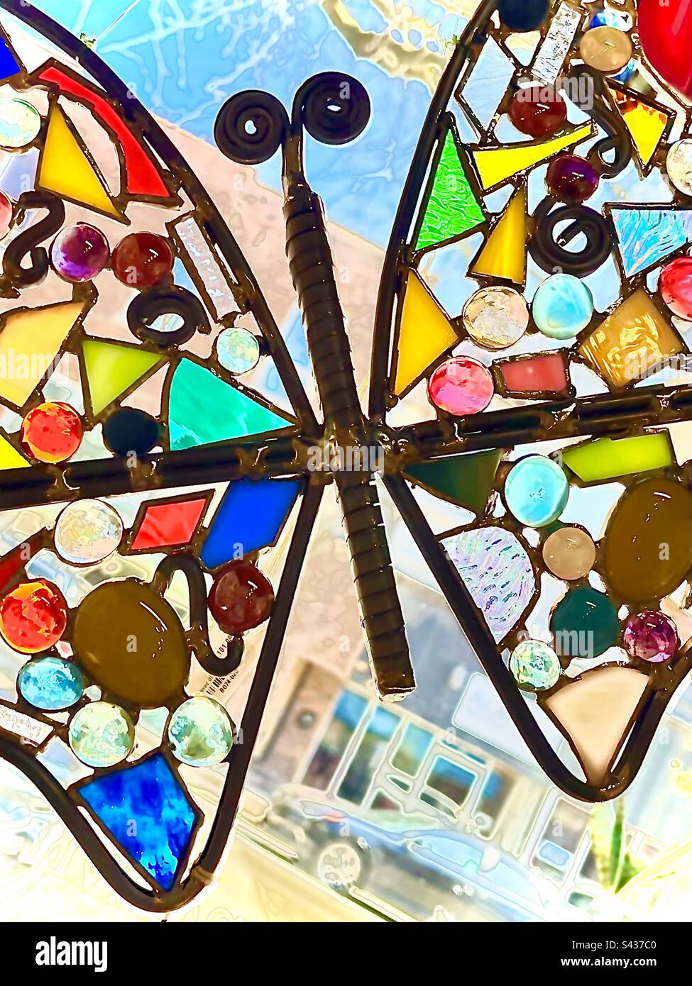 Colorful mosaic butterfly displayed in sunny window. Includes print space. - Smartphone Captured Stock Image
