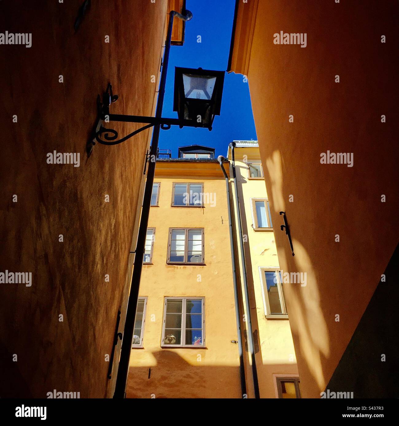 The beautiful shadowy orange and yellow painted exteriors of traditional buildings on the narrow streets of Stockholm Old Town Gamla Stan in Sweden - Smartphone Captured Stock Image