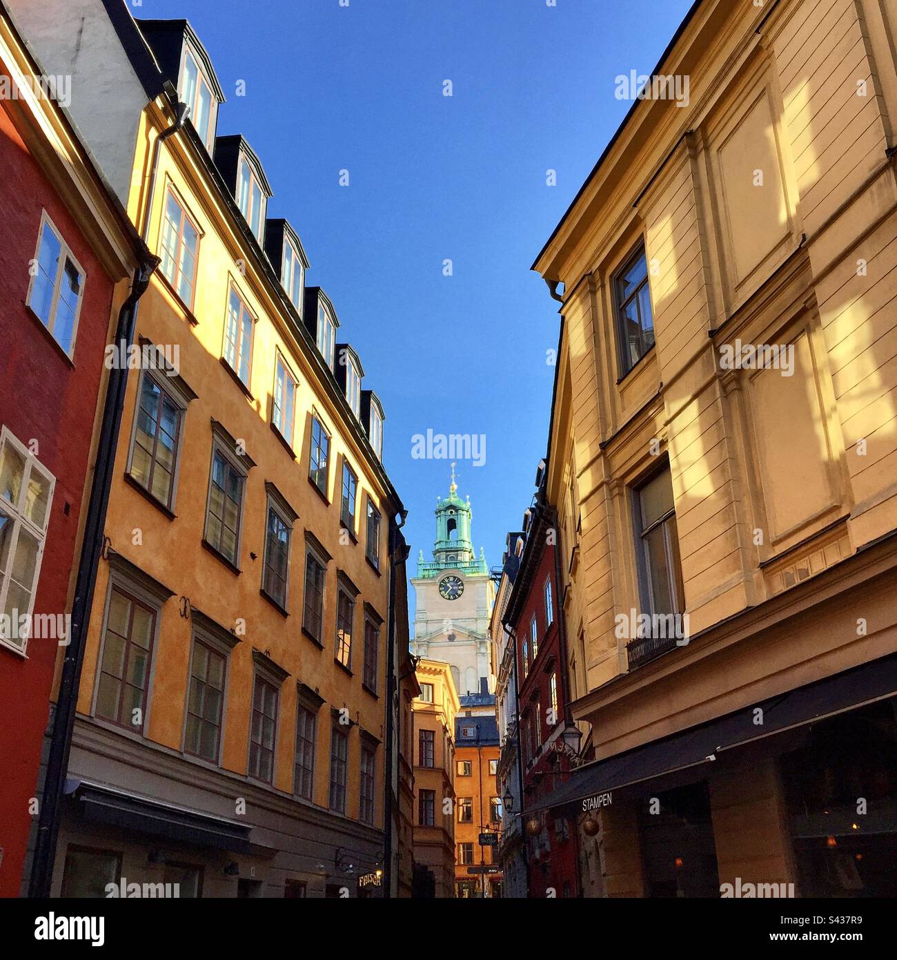 The beautiful shadowy orange and yellow painted exteriors of traditional buildings on the narrow streets of Stockholm Old Town Gamla Stan in Sweden - Smartphone Captured Stock Image