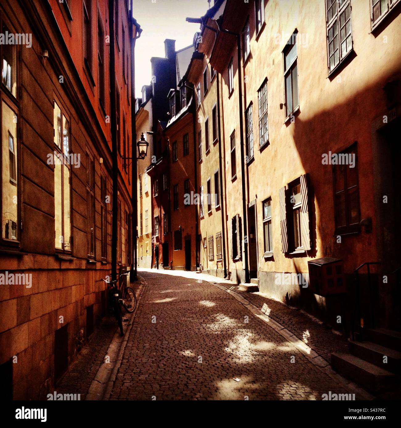 The beautiful shadowy orange and yellow painted exteriors of traditional buildings on the narrow streets of Stockholm Old Town Gamla Stan in Sweden - Smartphone Captured Stock Image