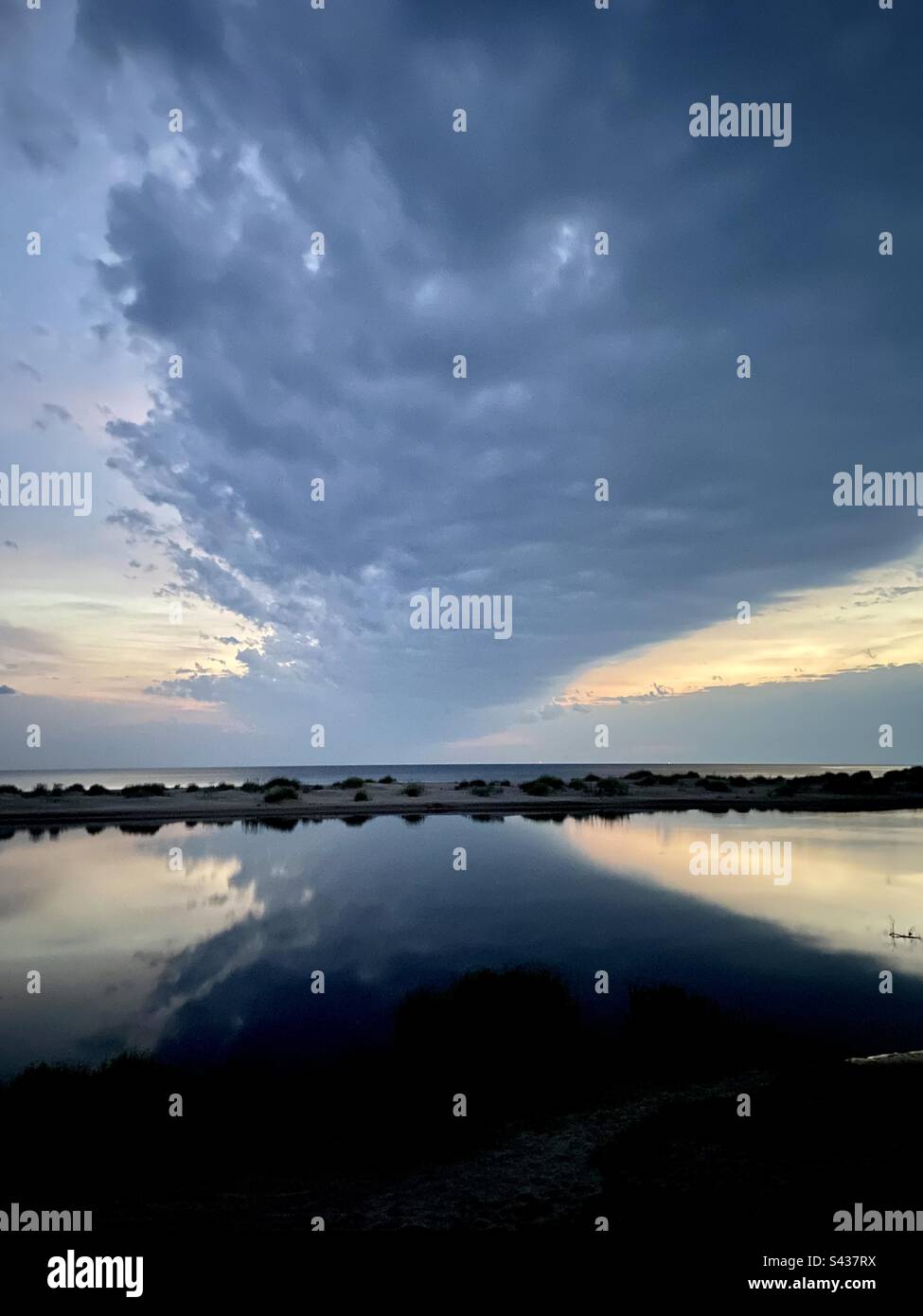 Baltic sea in Latvia at the place where river Irbe flows into the sea on a summer evening right before the sunset. There are reflections of clouds in the water. - Smartphone Captured Stock Image