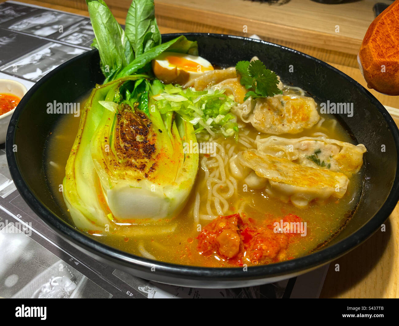 A bowl of ramen with gyoza and broth in a restaurant. - Smartphone Captured Stock Image