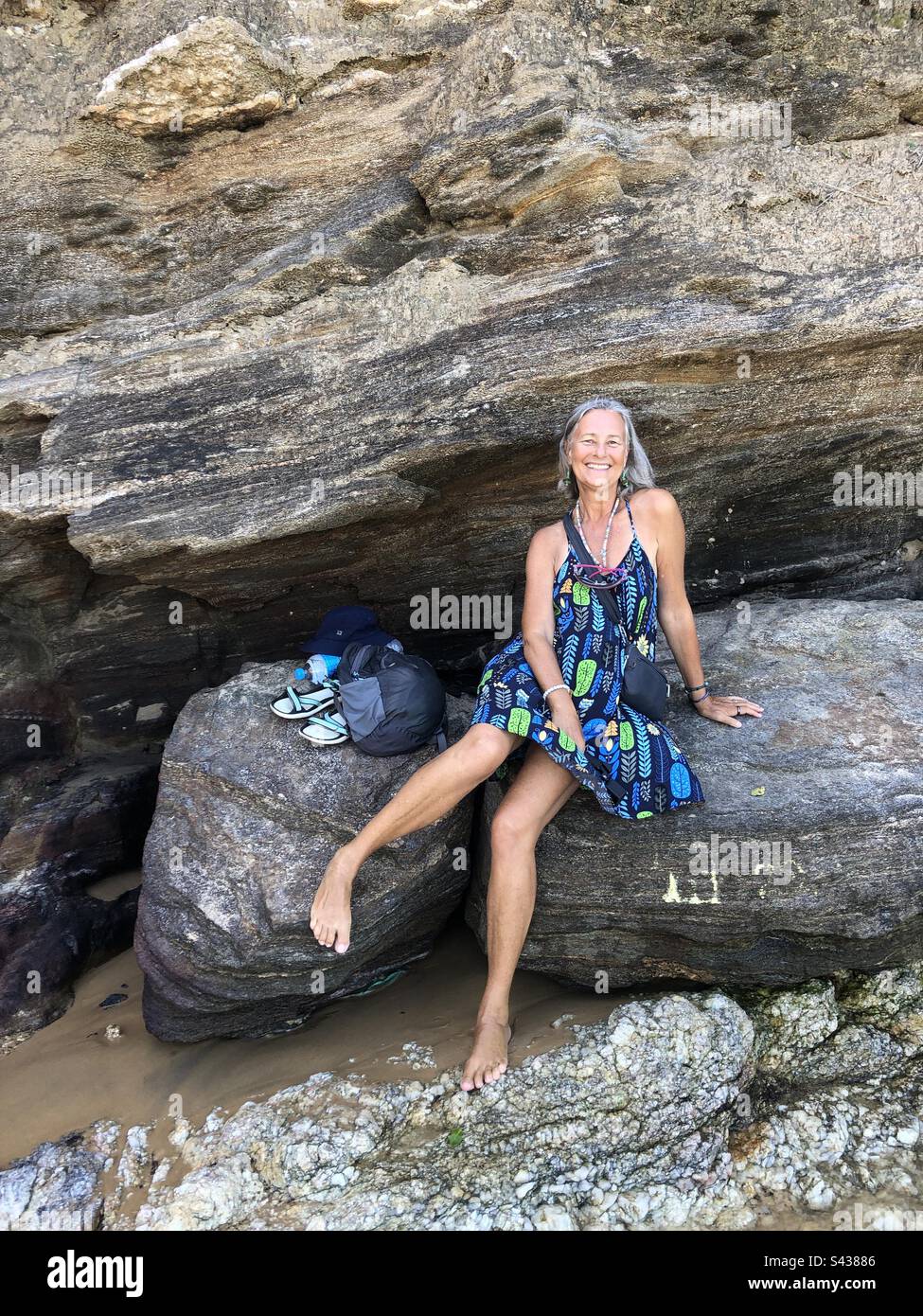 A woman sitting on a rock happy and smiling. - Smartphone Captured Stock Image