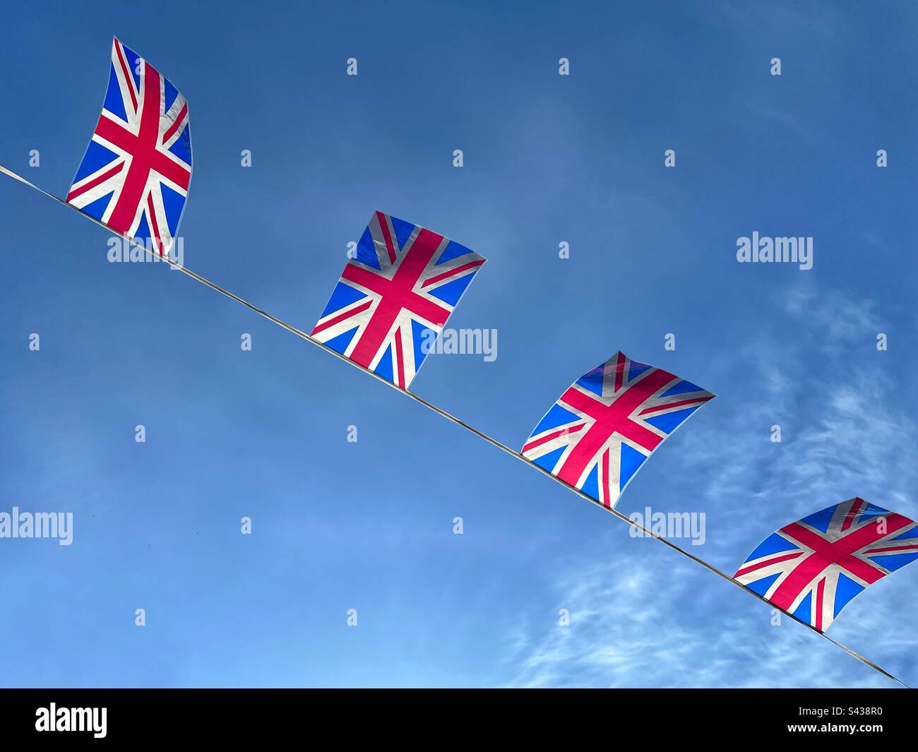 Union Jack flags against blue sky Stock Photo