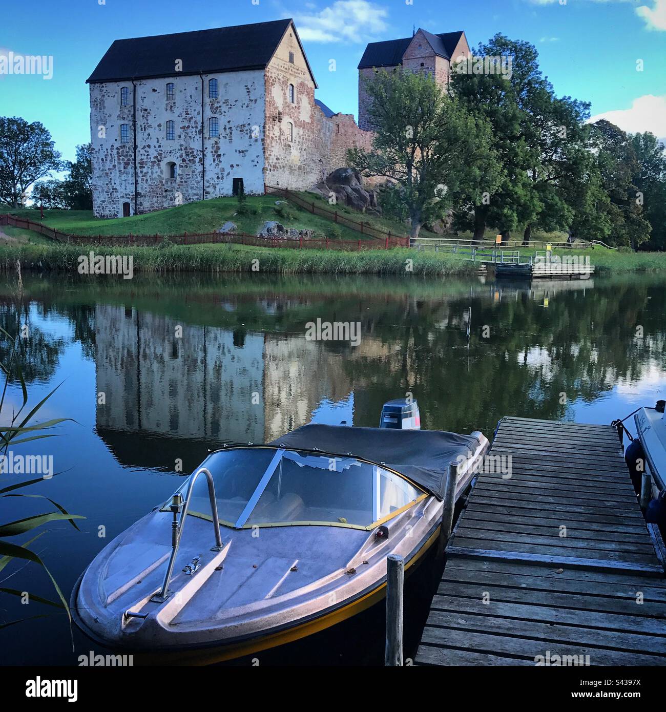 A speedboat at a lake pier next to the beautiful ancient castle of Kastelholm in the Åland Islands archipelago in the Baltic Sea region of Finland on a summer evening. - Smartphone Captured Stock Image A speedboat at a lake pier next to the beautiful ancient castle of Kastelholm in the Åland Islands archipelago in the Baltic Sea region of Finland on a summer evening. - Smartphone Captured Stock Image
