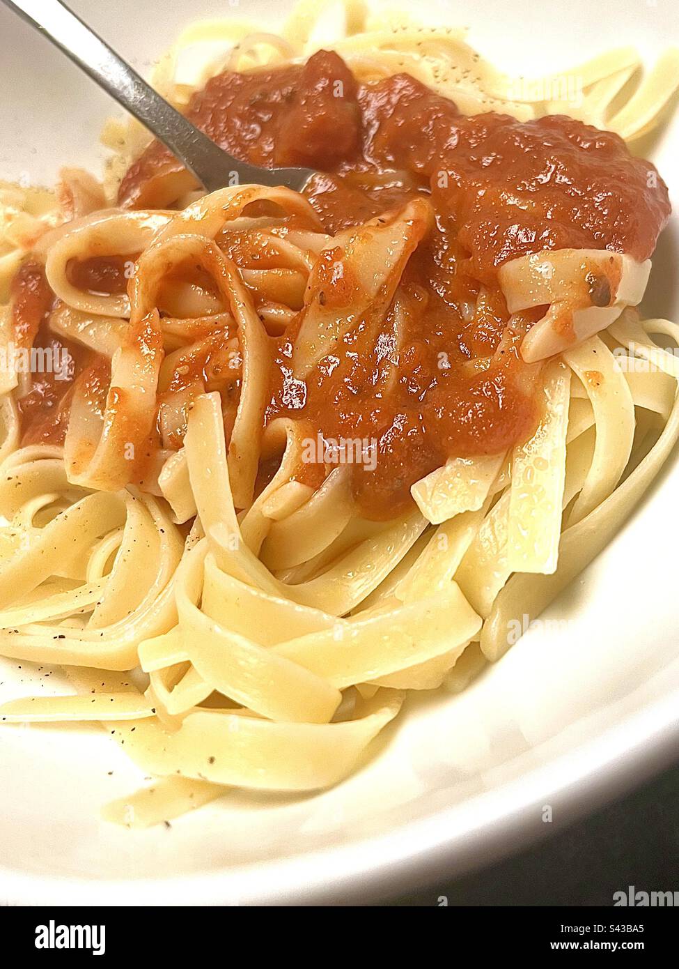 Fresh pasta with marinara sauce in white bowl with fork. - Smartphone Captured Stock Image