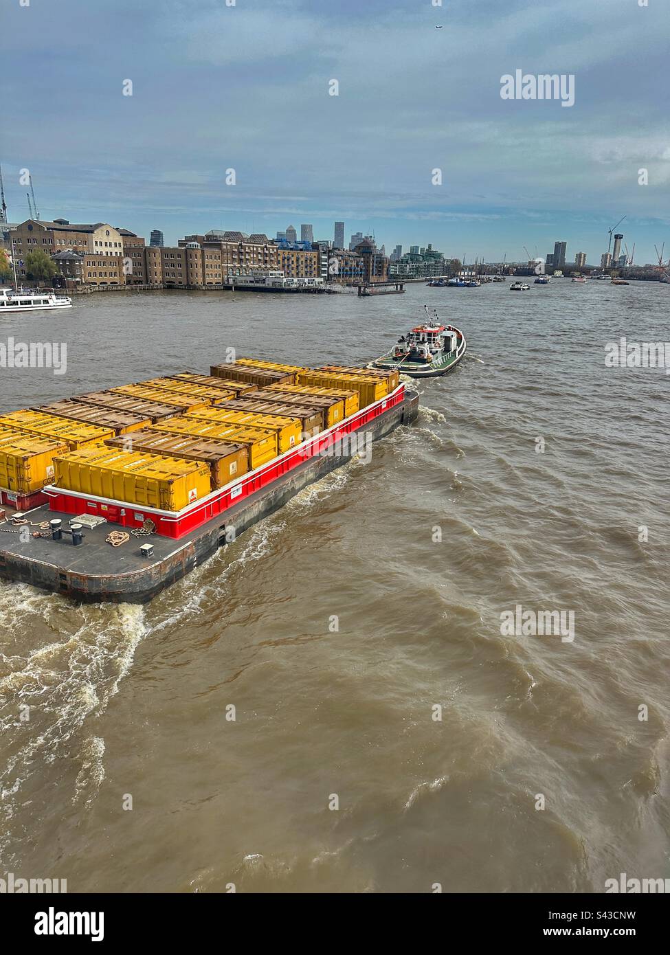 Tug boat pulling barge loaded with shipping containers on the River Thames, London, England - Smartphone Captured Stock Image
