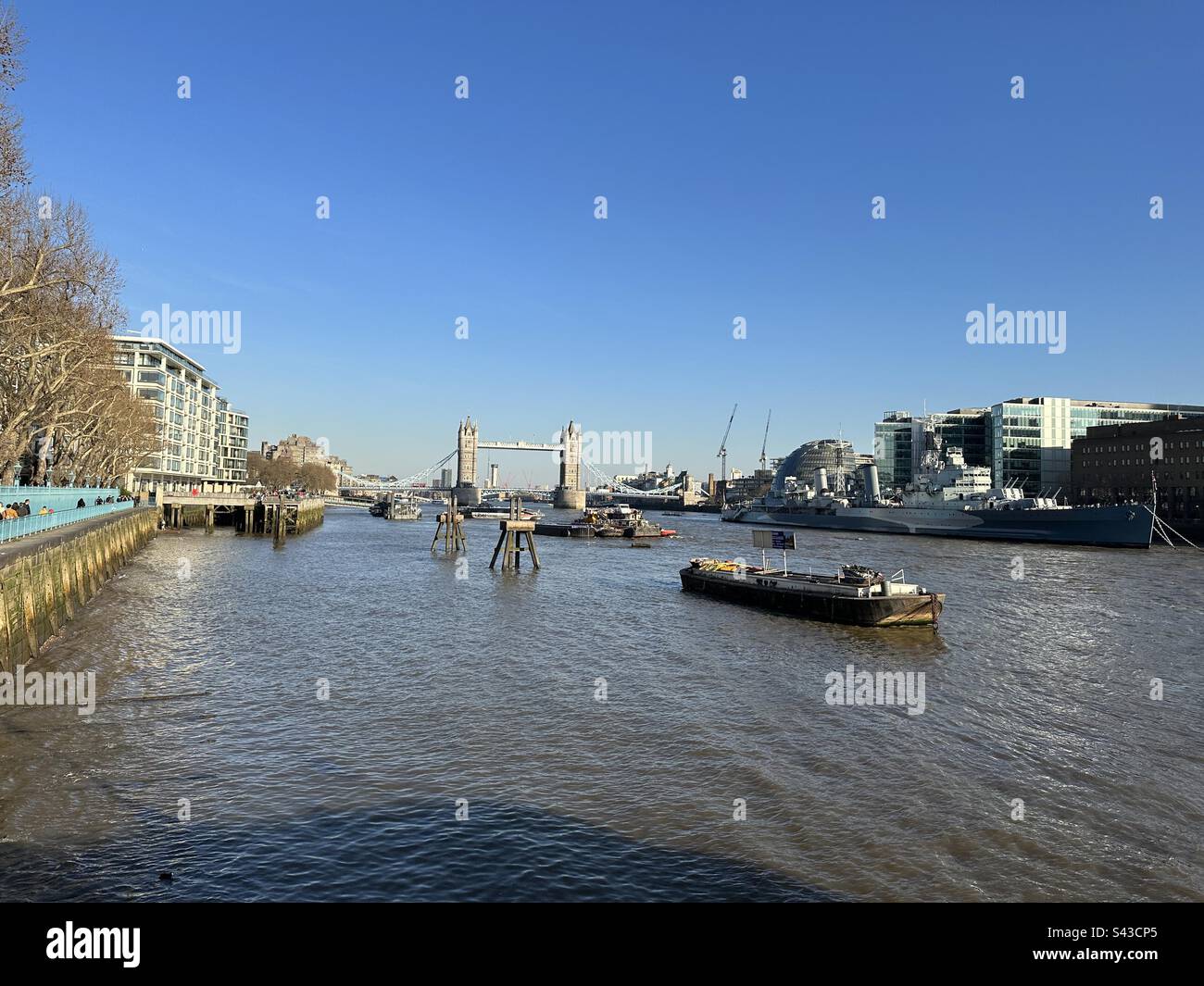 Tower Bridge and River Thames with moored boats and city buildings on north and south banks of the river, London, England Stock Photo