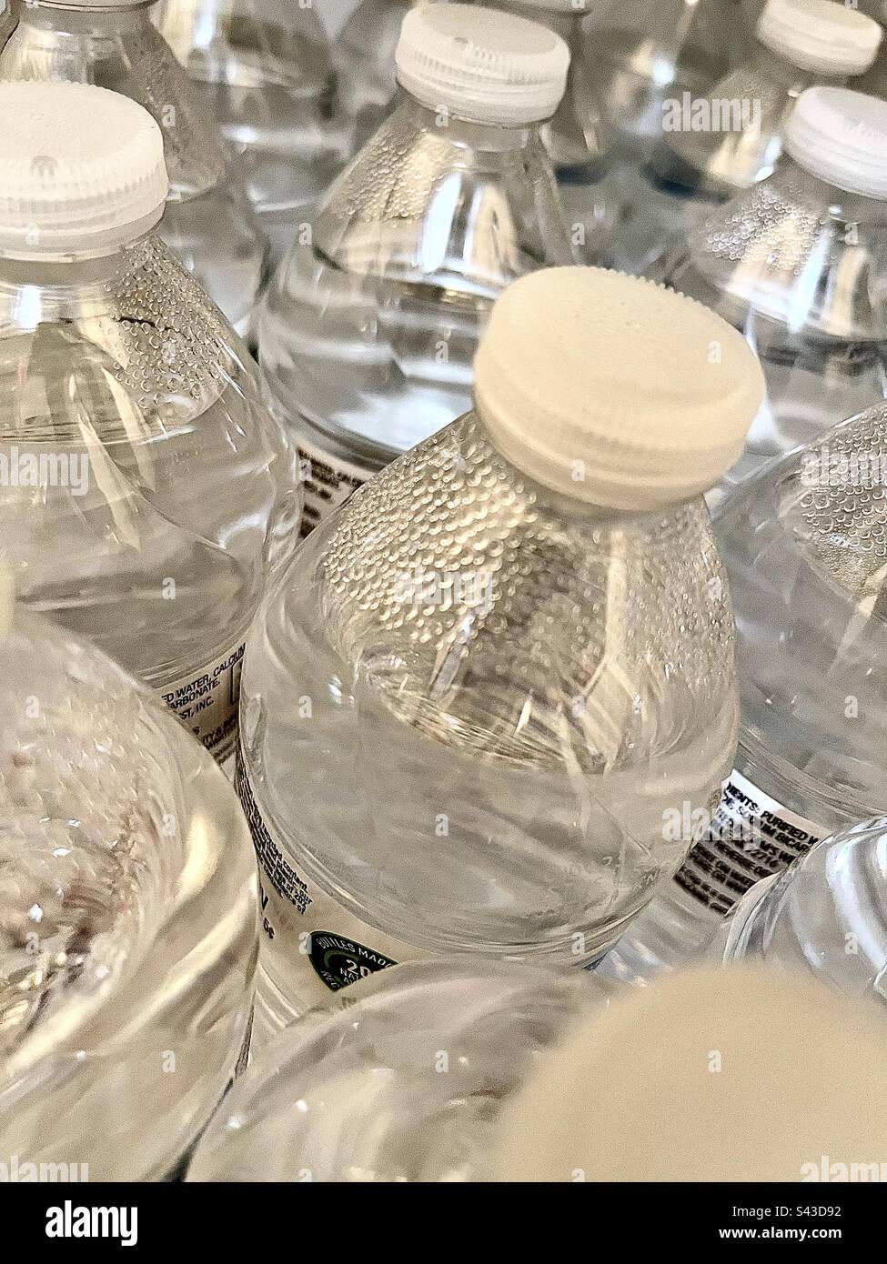 Top view of water bottles with white lids fill entire frame. - Smartphone Captured Stock Image
