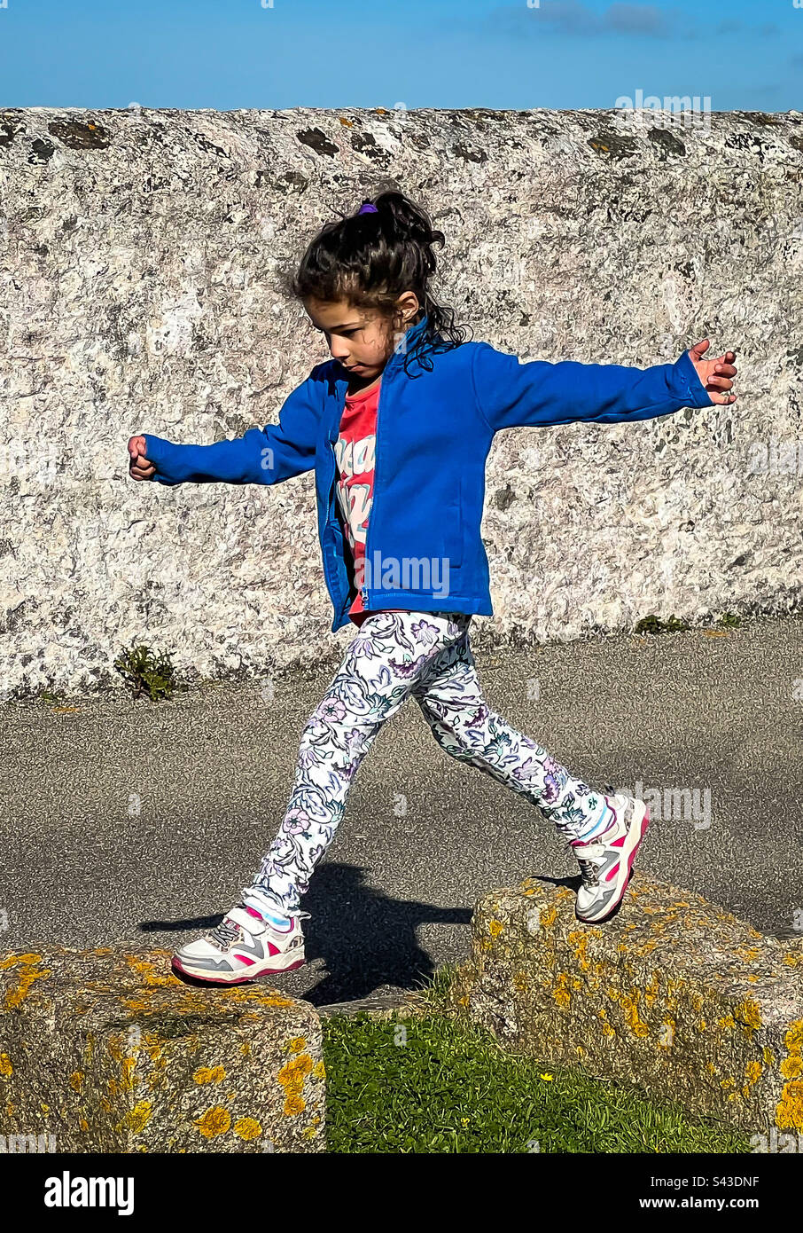 Mixed race girl jumping between stone blocks. - Smartphone Captured Stock Image