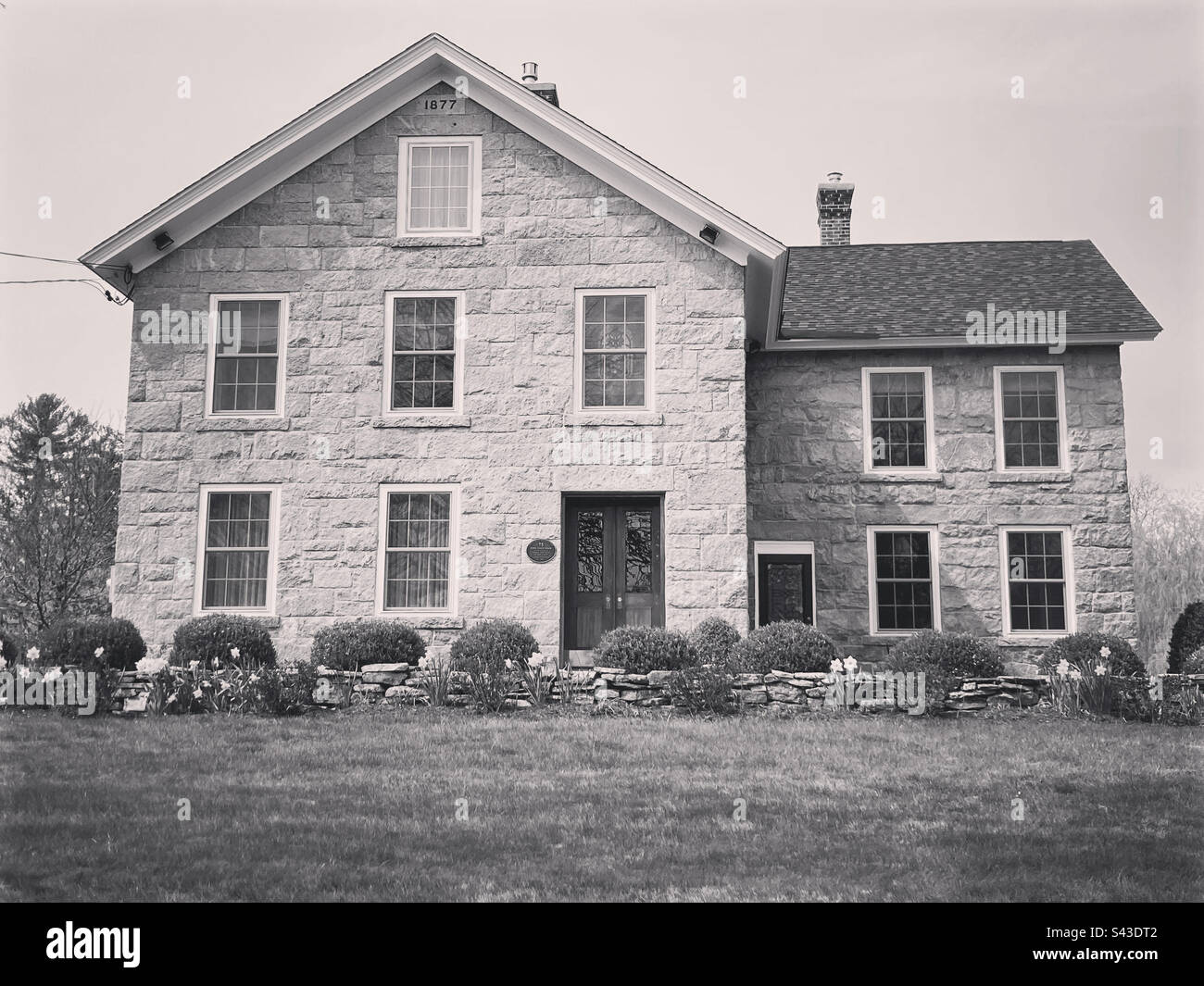 Beautiful, old stone house in Waterford, Connecticut, USA. Black and white filter. Built in 1877 with the year noted at the top of the roof line. - Smartphone Captured Stock Image