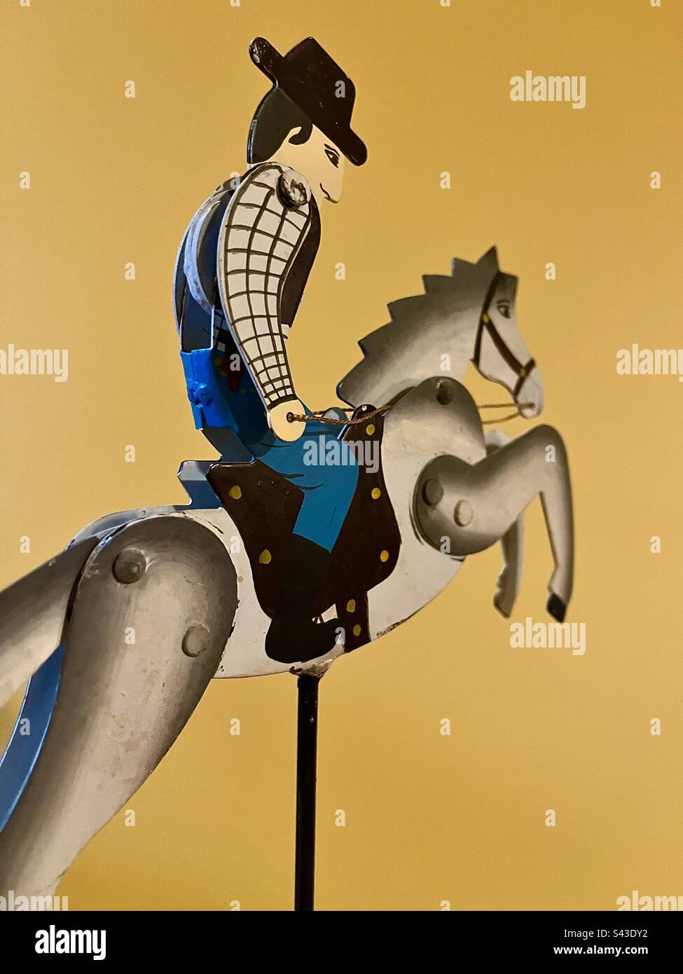 Vintage toy. Metal cowboy riding horse against solid yellow background. Includes print space. - Smartphone Captured Stock Image