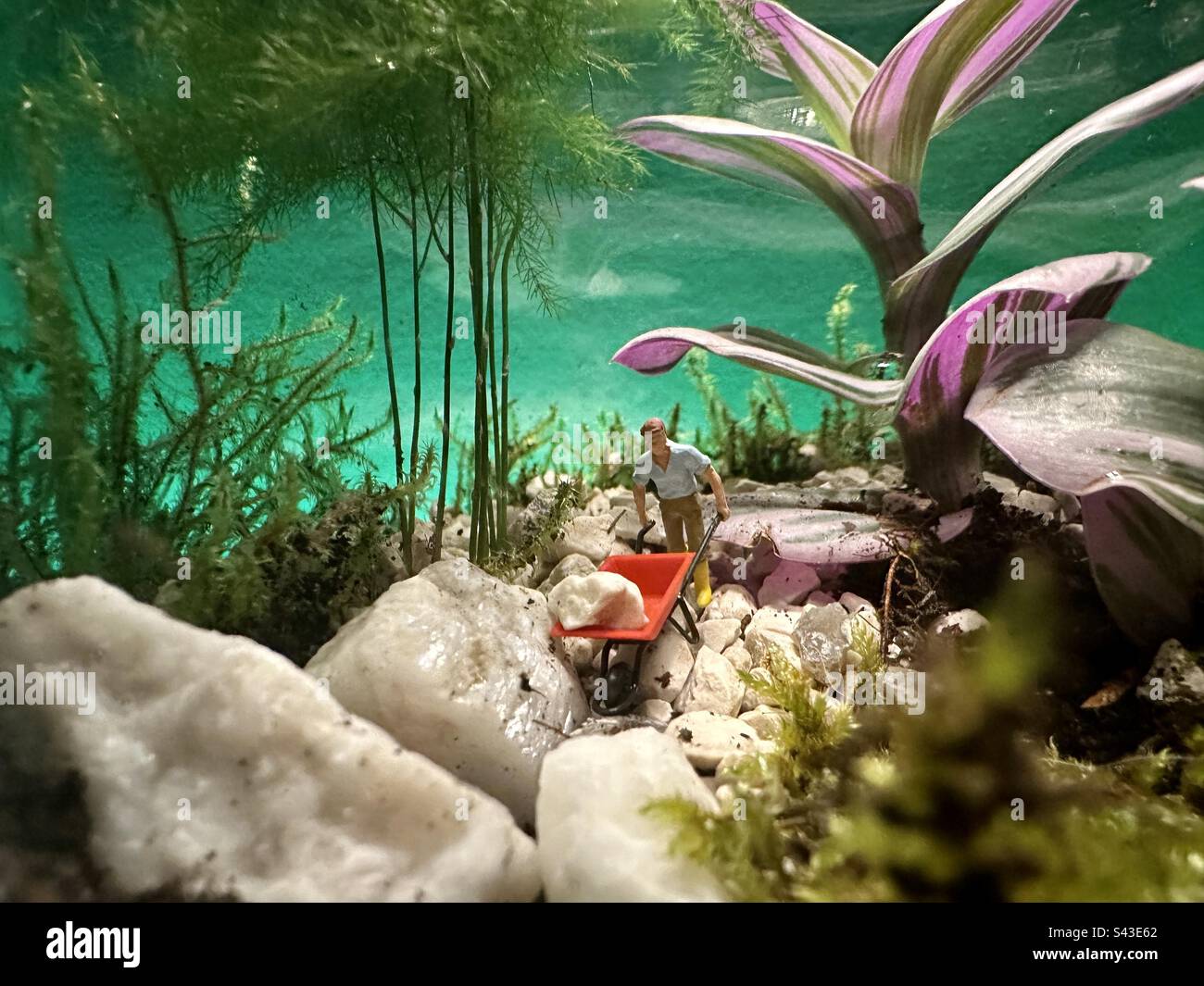 Miniature garden with a little person pushing a wheelbarrow on a rocky path - Smartphone Captured Stock Image