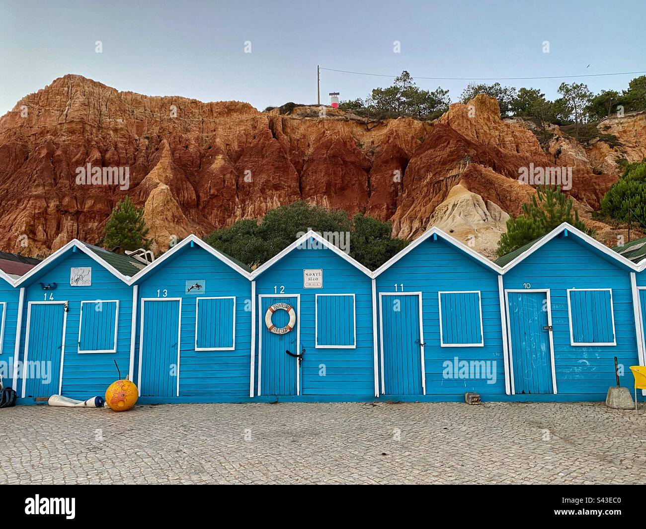 Blue wooden boat garages in front of sandstone rocks in Olhos de Água in Algarve, Portugal. - Smartphone Captured Stock Image
